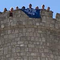 Students holding a GVSU flag over a tower edge